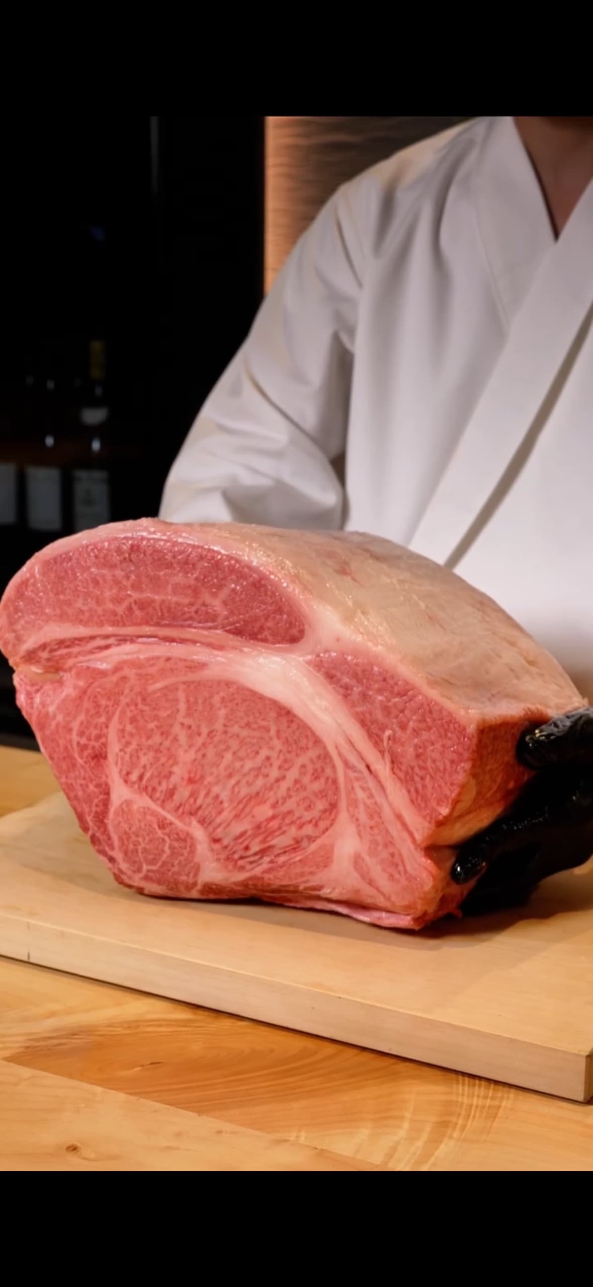 A chef presenting a premium cut of marbled Kobe beef