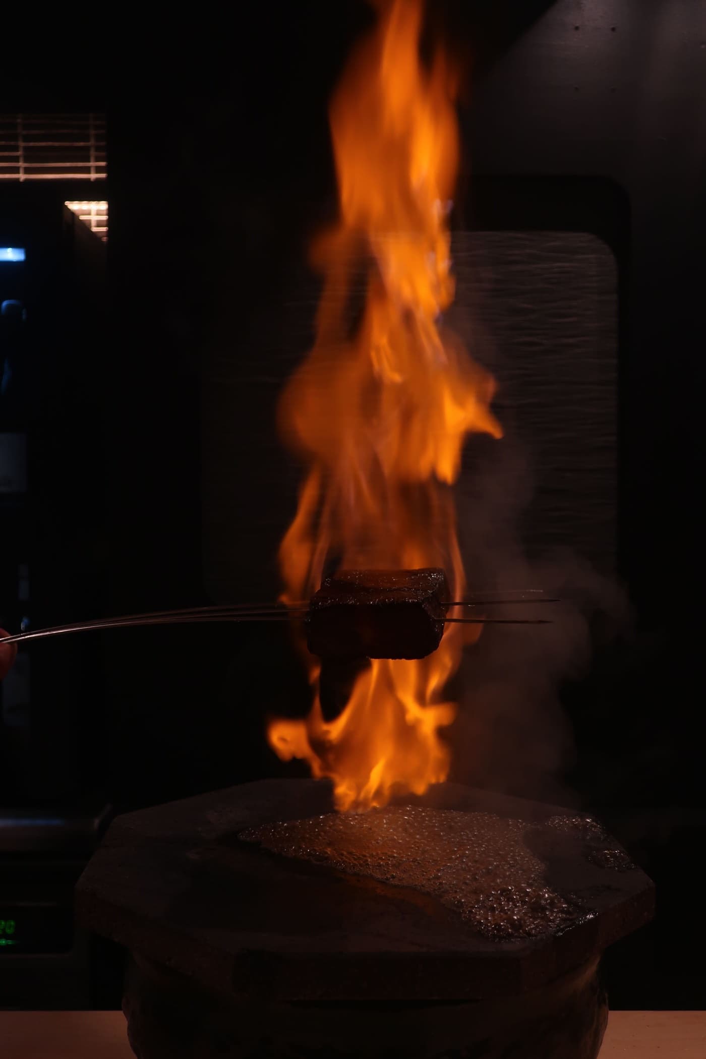 Kobe beef held over a dramatic open flame